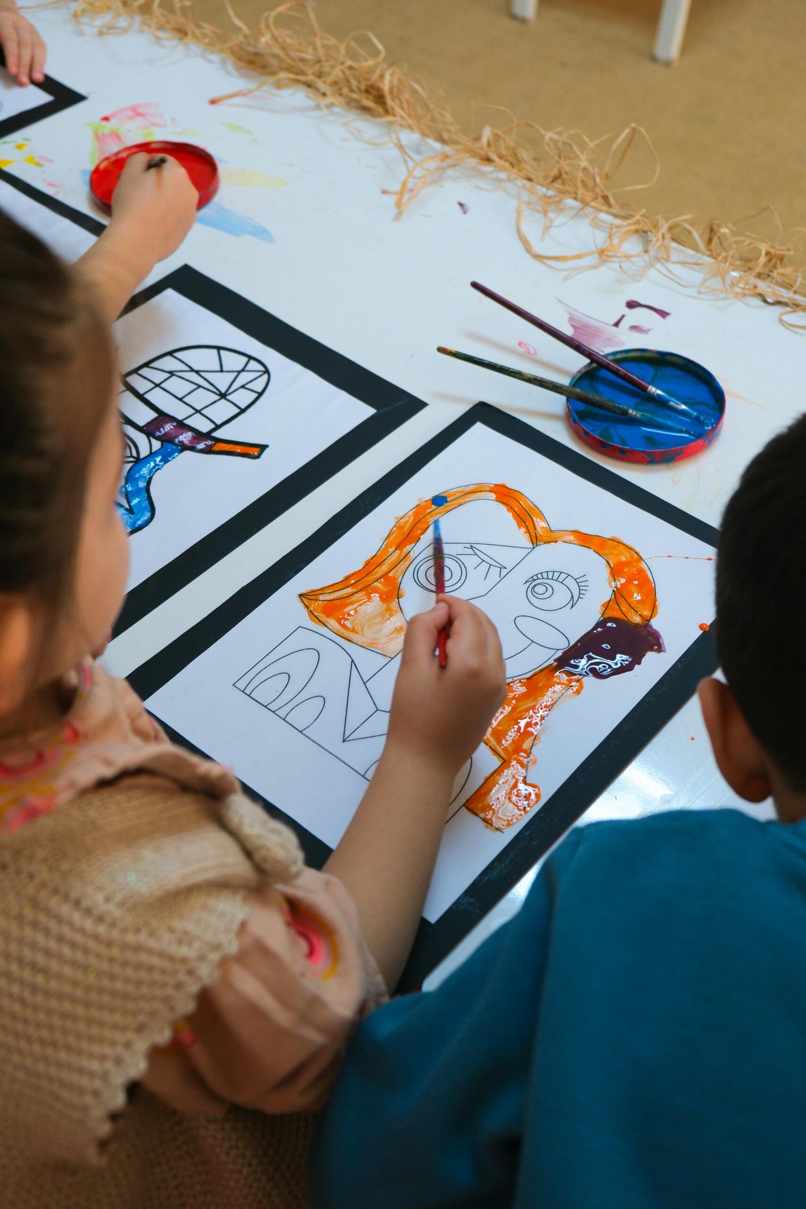 Children painting colorful and abstract art projects in a school setting. Focus on creativity and education.